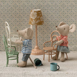 Two toy mice in a miniature room setting with furniture and decor.